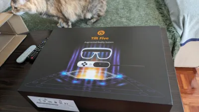 Caja de un sistema Tilt Five y una gata más interesada en la caja de cartón